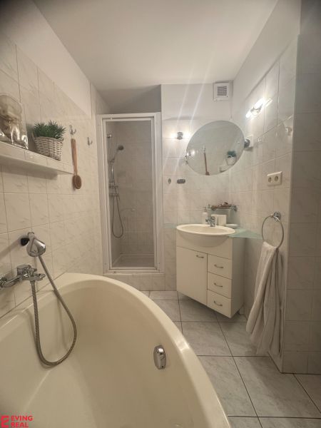 Bathroom with a bathtub, sink, and shower in a studio apartment.