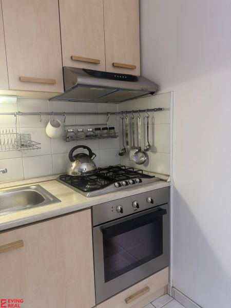 A kitchen in a studio apartment with a gas stove and cabinets in a light decor.