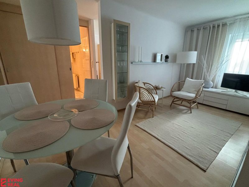 A bright living space with a dining table and wood-patterned flooring in a studio apartment.