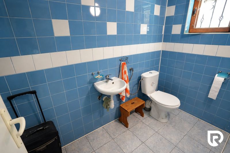 Bathroom in a family house with blue tiles, a sink, and a toilet.