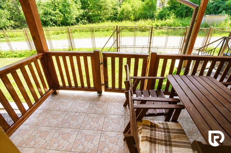 A wooden terrace with a view of the garden in a family house.