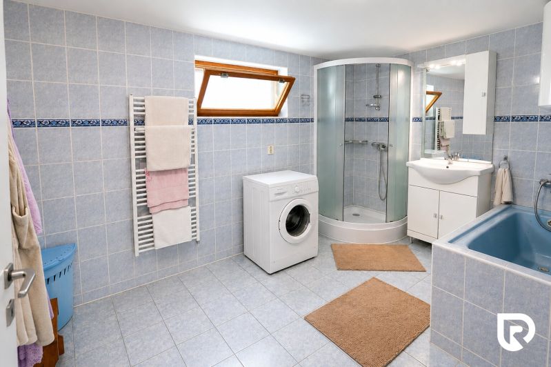 A bathroom in a family house with a bathtub, shower, and washing machine.