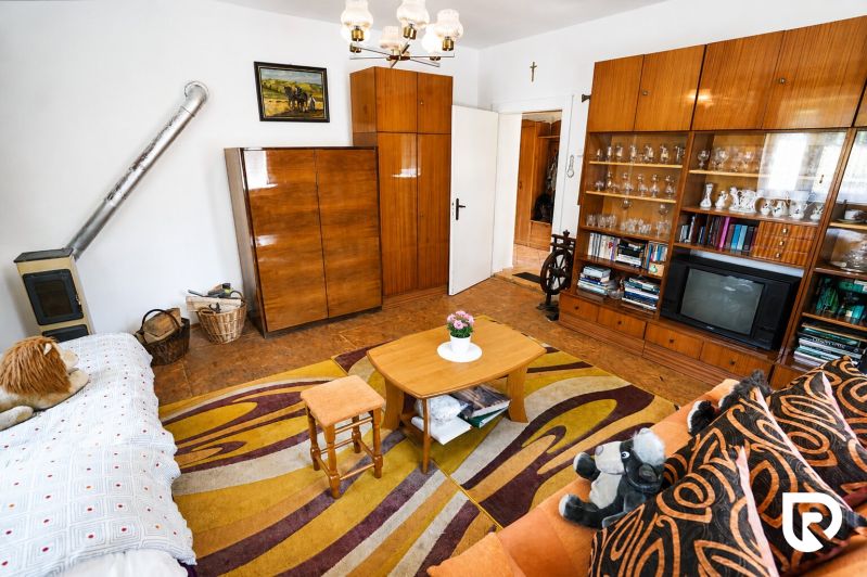 Living room in a family house with a carpet, furniture, television, and a stove.