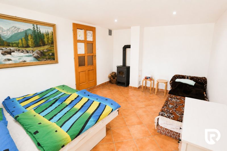 A bedroom with colorful bedding, a sofa, a stove, and a painting in a family house.