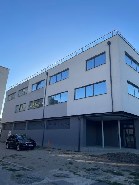 Commercial premises in Levice at Komenského 2A 2B with glass windows and a parked car.