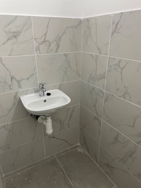 A sink and tiles in commercial premises with a marble pattern.