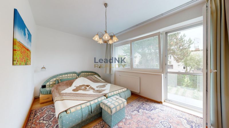 Bedroom in a 3-room apartment with a large window, colorful carpet, and double bed.