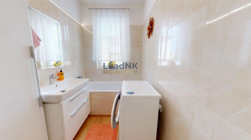 A bathroom in a 3-room apartment with a bathtub, sink, washing machine, and window.
