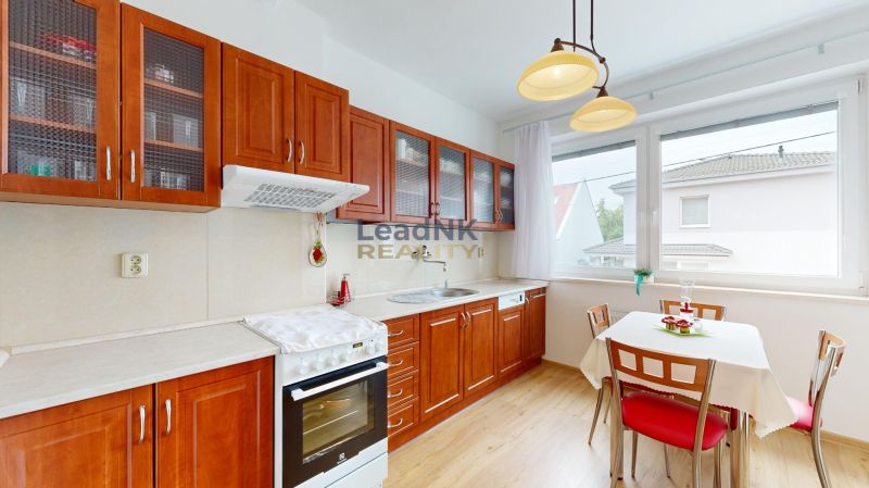 A kitchen with wooden decor and a dining area with chairs.