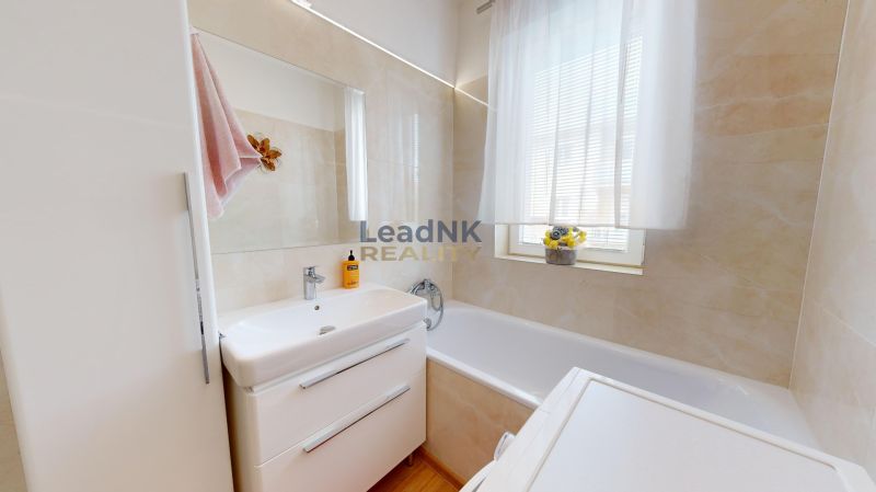 A bathroom in a 3-room apartment with a bathtub, a sink, and storage space.