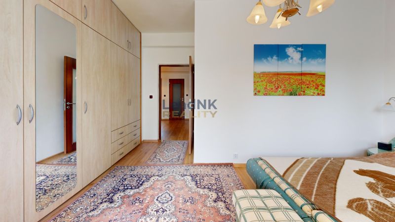 Bedroom in a 3-room apartment with a wooden decor floor, carpet, and a painting on the wall.