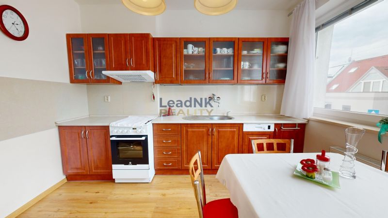A kitchen in a 3-room apartment with wooden cabinets, a stove, and a floor with a wooden decor.