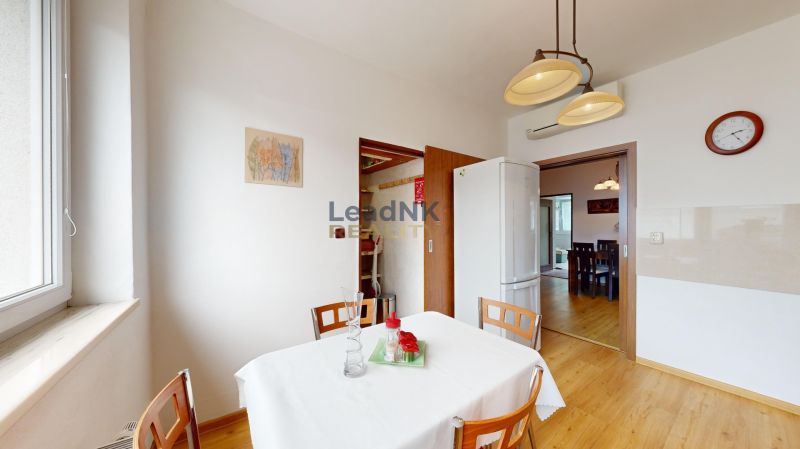 A kitchen in a 3-room apartment with a wooden decor floor, a white table, and chairs.