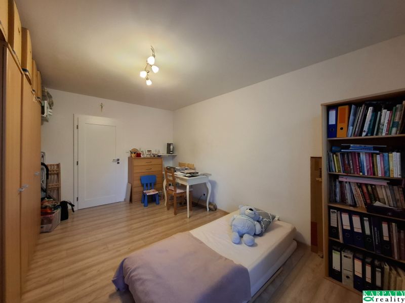 A room with a desk, a bed, and a floor with a wooden decor in a 3-room apartment.