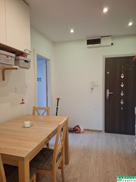 Dining room in a 3-room apartment with a wooden decor floor and a wooden table.