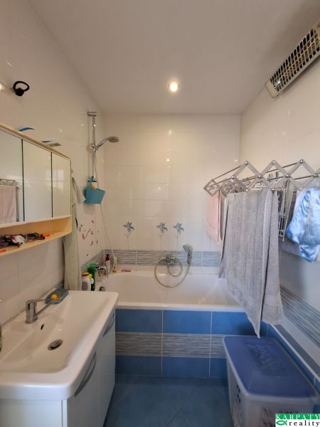 A bathroom in a 3-room apartment with a bathtub, a mirrored cabinet, and tiles.