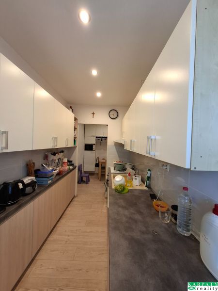 A kitchen in a 3-room apartment with white cabinets and a wood-patterned floor.