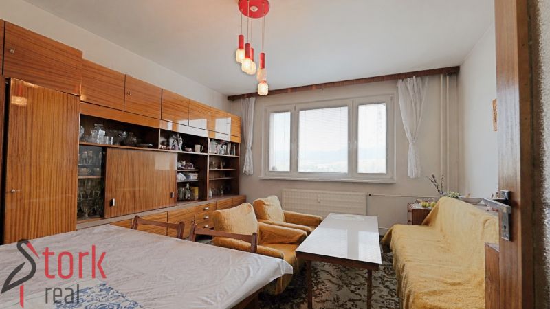 Living room in a 2-room apartment with carpet patterns and yellow sofas.