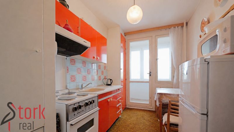 A kitchen in a 2-room apartment with orange cabinets and balcony doors.