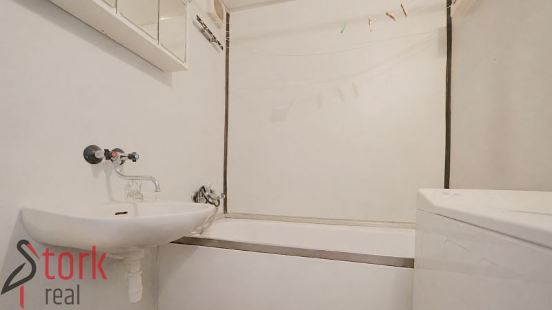 Bathroom in a 2-room apartment with a bathtub, sink, and washing machine.