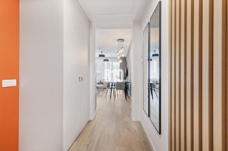 A hallway with a wooden decor floor, a mirror, and an entrance to the living area.