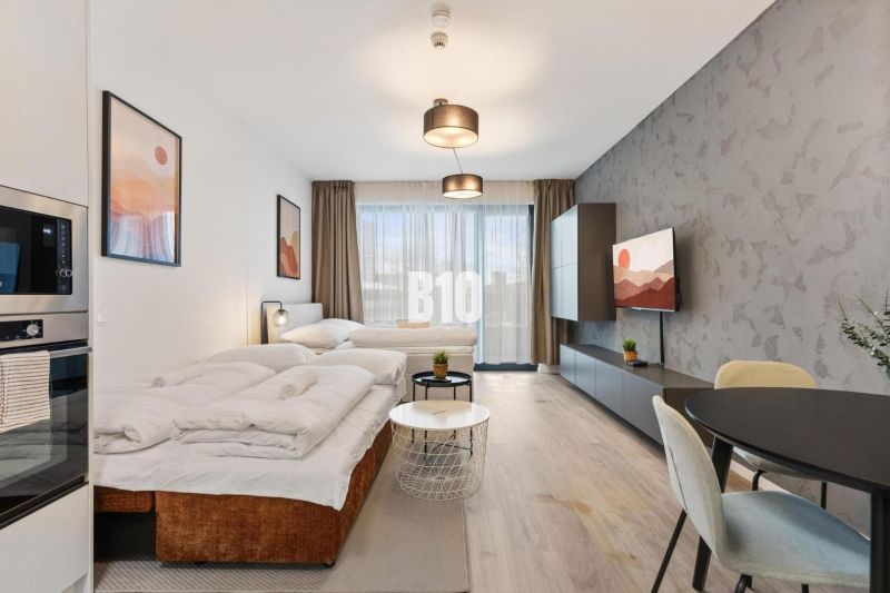 A comfortable living space in a studio apartment with wood-patterned flooring and large windows.