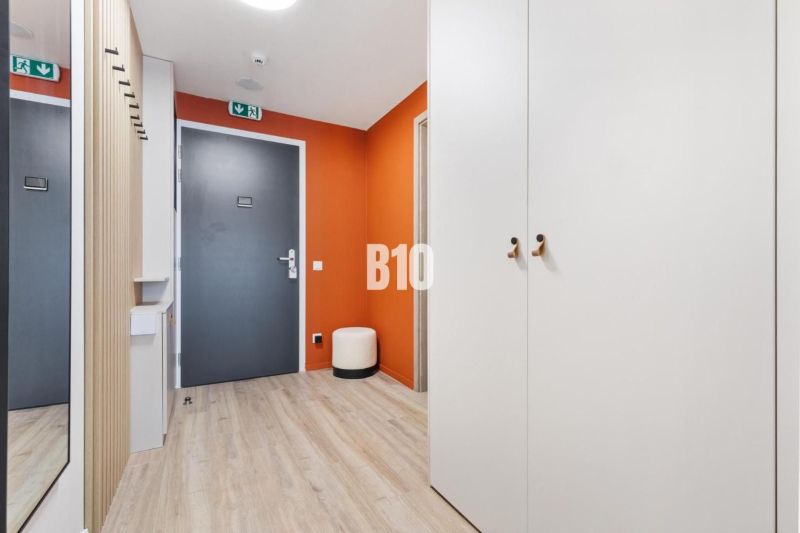 Entrance hall of a one-room apartment with a wooden decor floor and an orange wall.