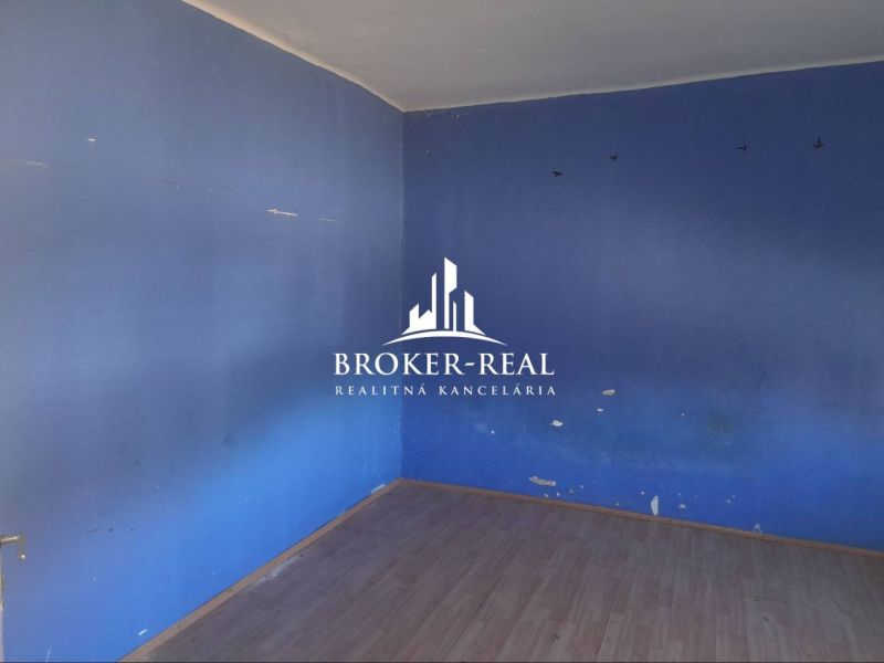 A room in a family house with blue walls and a floor with a wooden decor.