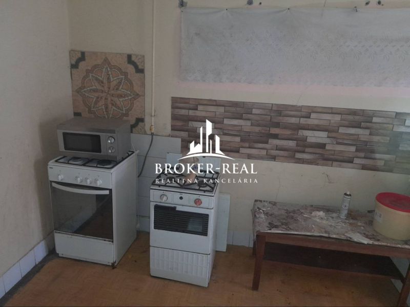 A kitchen in a family house with a gas stove, microwave, and decorative tiles on the wall.