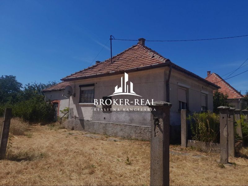 A family house in Csobád with plastered walls, a tiled roof, and neglected surroundings.