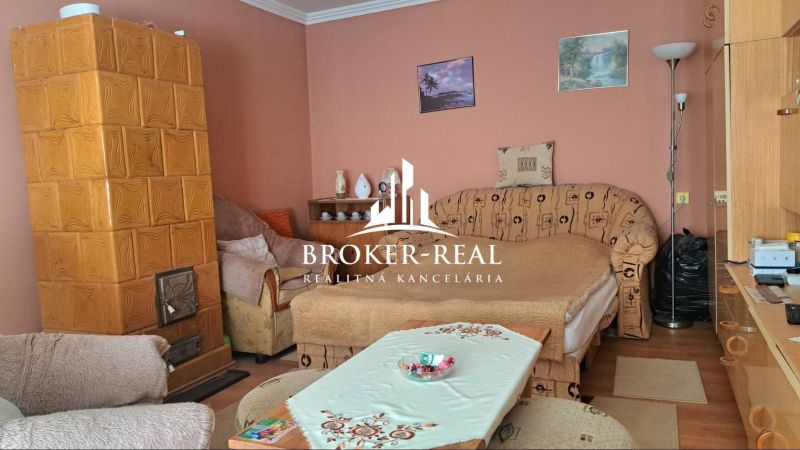 Living room with a tiled stove and a sofa in a family house.