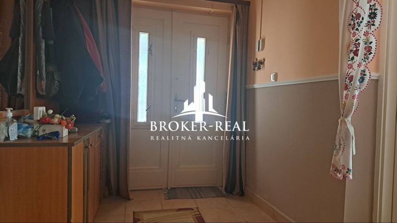 Entrance hall in a family house with a cabinet, floral decoration, and white doors.