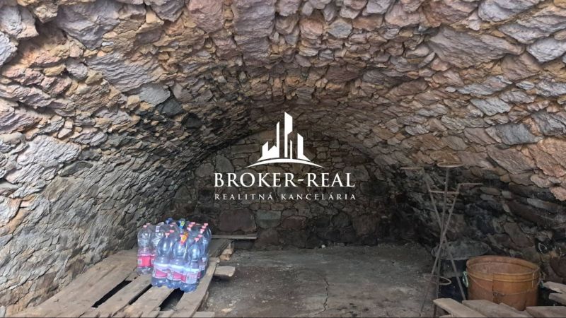 A stone cellar in a family house, with a shelf and bottles of water.