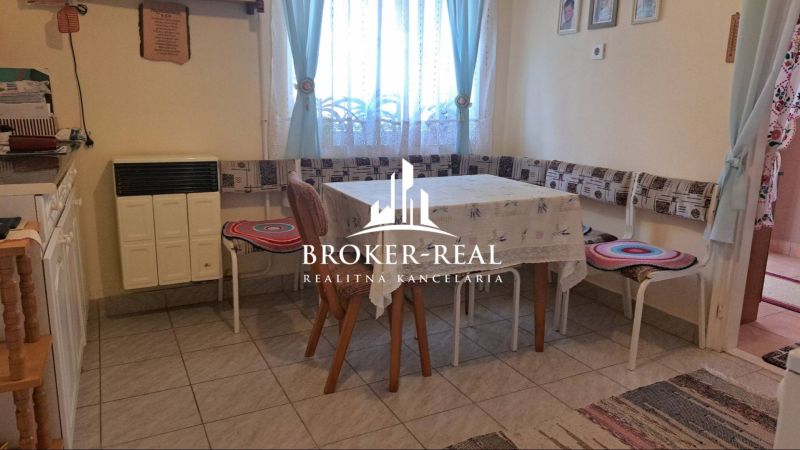 Dining room in a family house with a stove, table, and chairs with cushions.