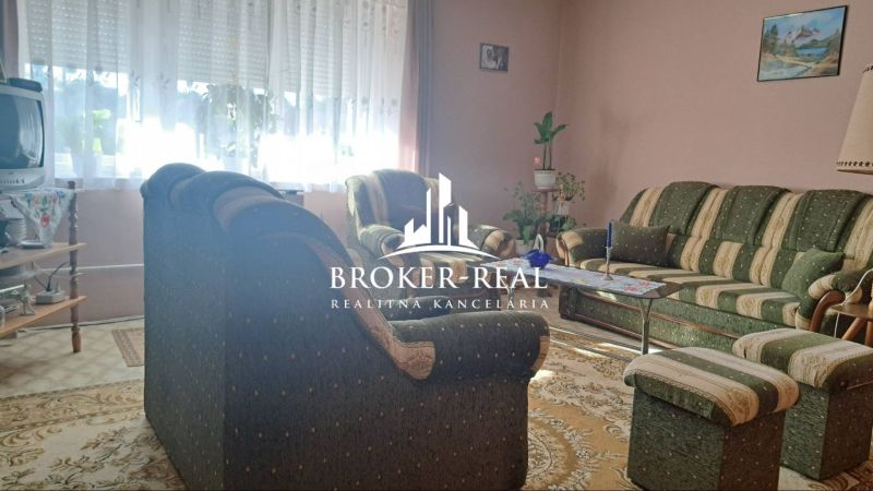 Living room with carpets, a green sofa set, and a television in a family house.