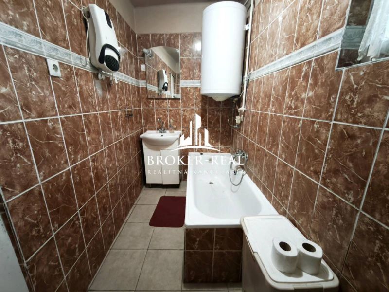A bathroom in a family house with brown tiles and a bathtub.