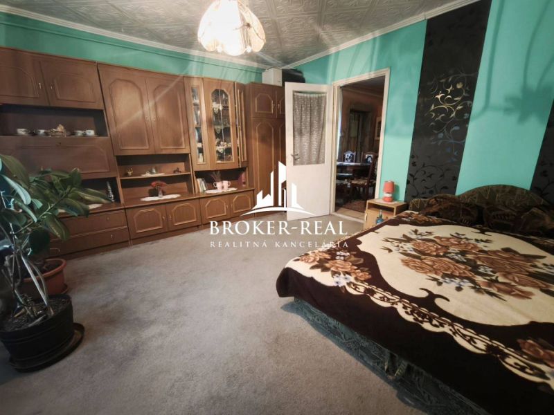 A room in a family house with wooden furniture, green walls, and a comfortable bed.