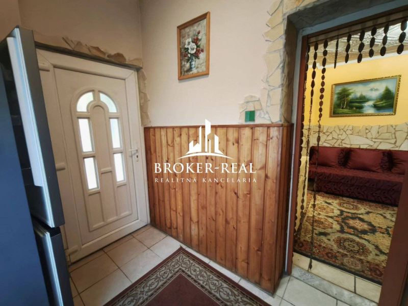 Entrance hall of a family house with light tiles and wooden paneling.