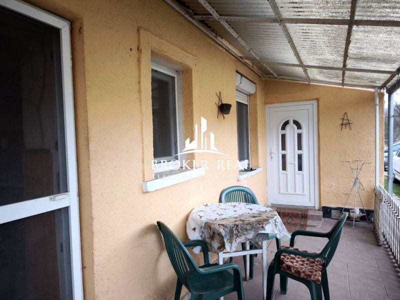 The terrace of a family house in Bódvaszilas with a table and plastic chairs on a paved floor.
