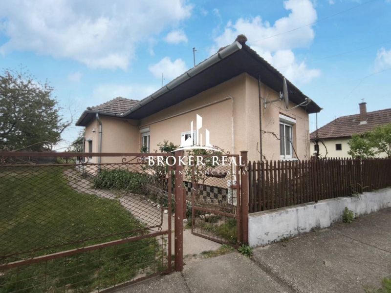 A family house in Bódvaszilas surrounded by a garden, with white plaster and a fence.