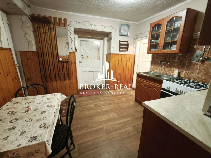 A kitchen in a family house with a wooden decor floor, a dining table, and a kitchen unit.