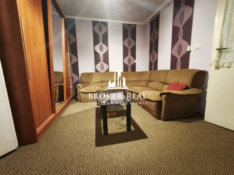 Living room in a family house with a striped sofa and colorful wallpaper.