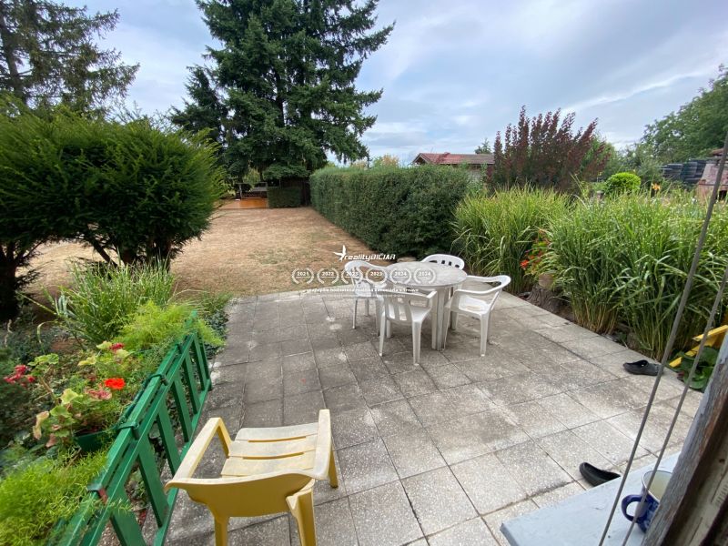 The garden of a family house in Zvončín with a paved terrace, chairs, and green plants.