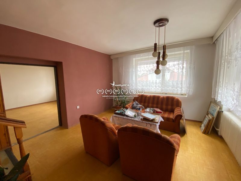 Living room of a family house with a wooden-patterned floor and a striped sofa.