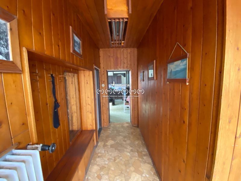 A hallway with wooden paneling inside a family house, with colorful paintings on the walls.