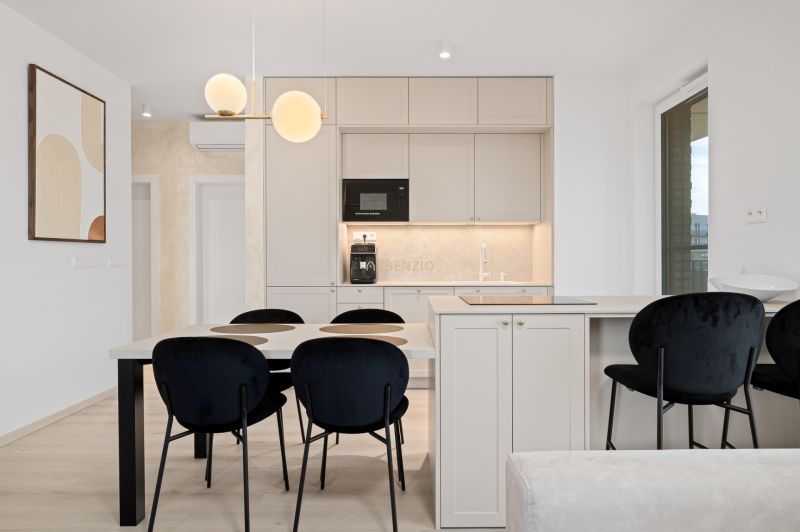 A kitchen in a 3-room apartment with a dining table and black chairs.