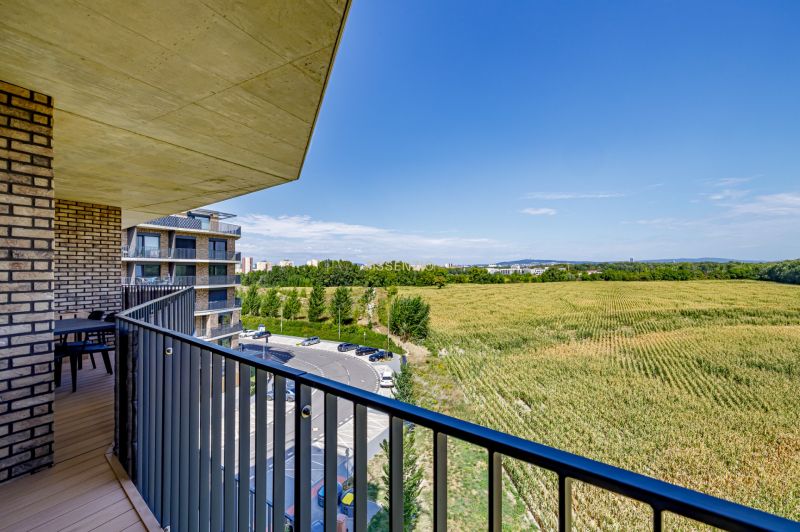 A balcony with a view of the field and buildings on Fialová Street, Bratislava-Petržalka, 3-room apartment.