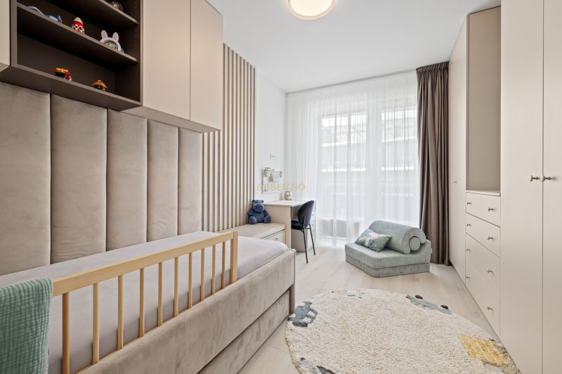 Children's room in a 3-room apartment with a bed, carpet, and shelves with toys.