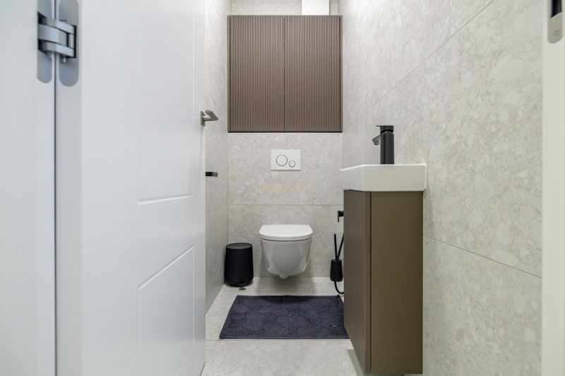 Elegant bathroom in a 3-room apartment with walls featuring a subtle pattern and a compact sink.