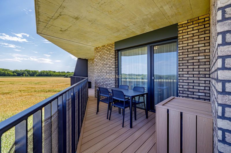 Sunny balcony with a view of the field in a 3-room apartment, brick cladding.